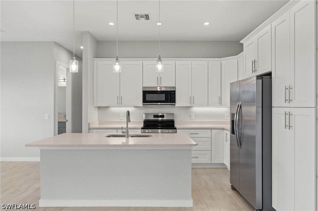 4713 6th Street W, Lehigh Acres, FL 33971 Gourmet kitchen with quartz island, shaker cabinets, and premium luxury vinyl plank (LVP) flooring upgrade.