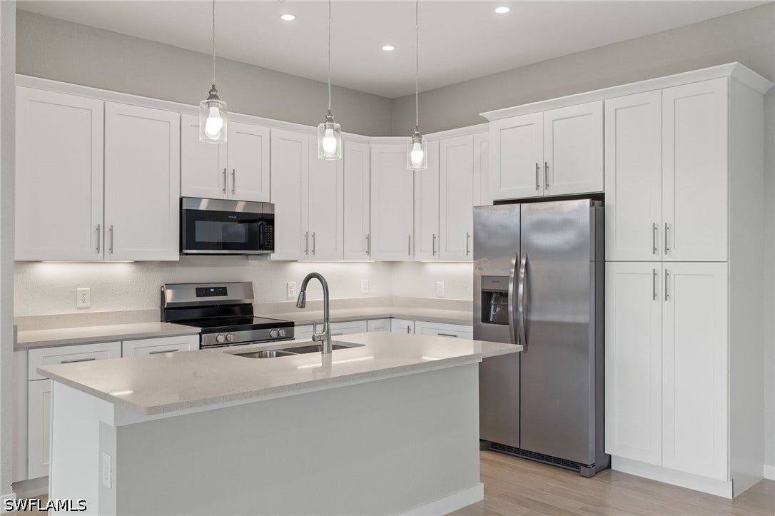4713 6th Street W, Lehigh Acres, FL 33971 Gourmet kitchen with quartz island, shaker cabinets, and premium luxury vinyl plank (LVP) flooring upgrade.