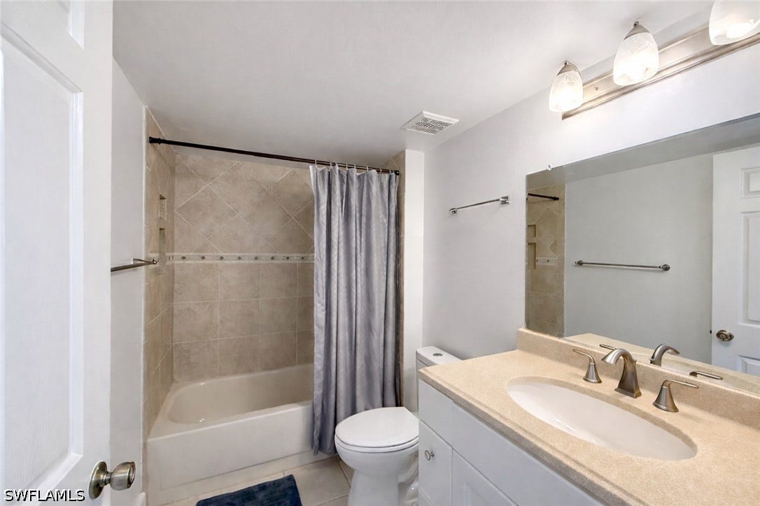 Full bathroom featuring vanity, light tile patterned floors, and shower / tub combo