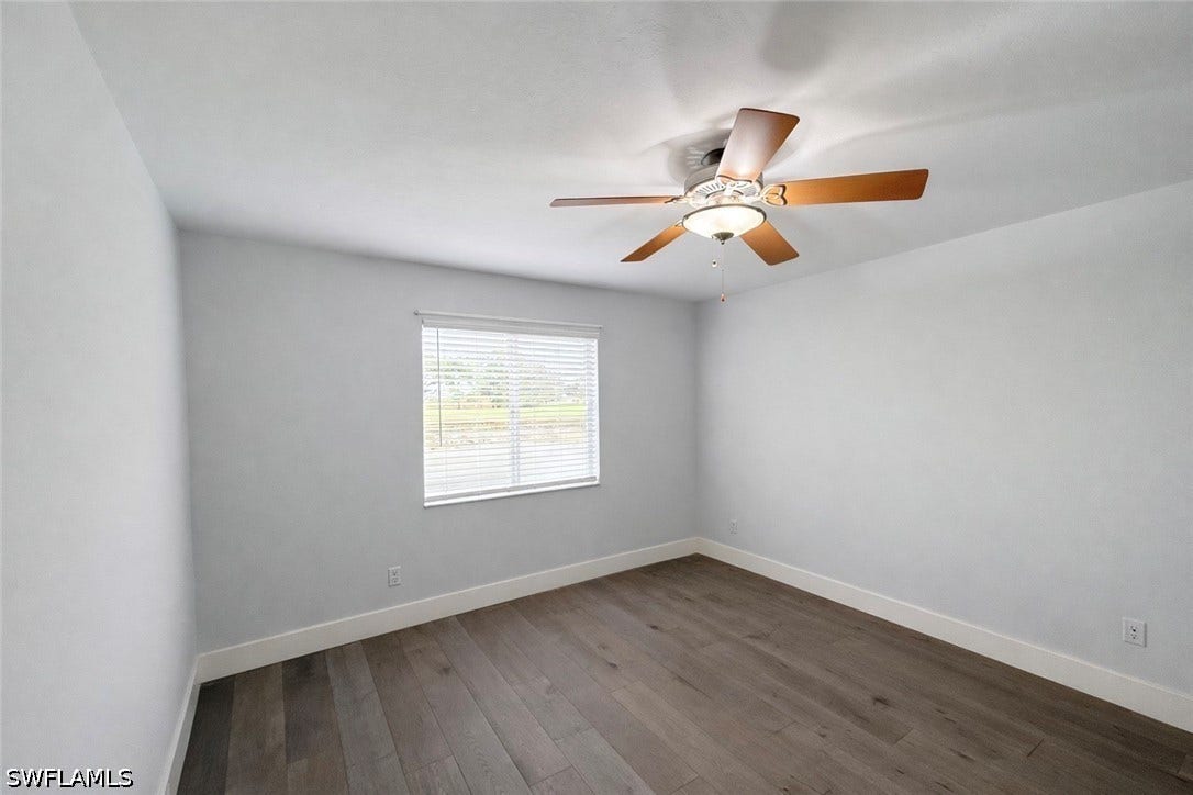 Spare room featuring dark wood-style flooring and ceiling fan