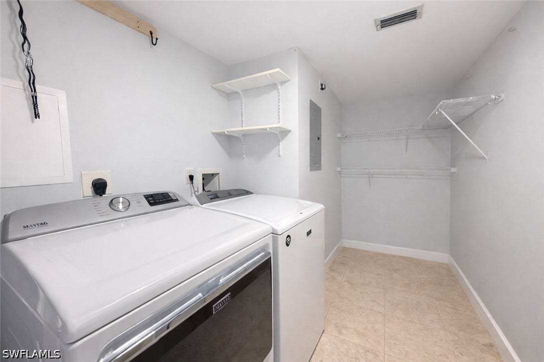 Laundry area with washer and clothes dryer, electric panel, and light tile patterned flooring