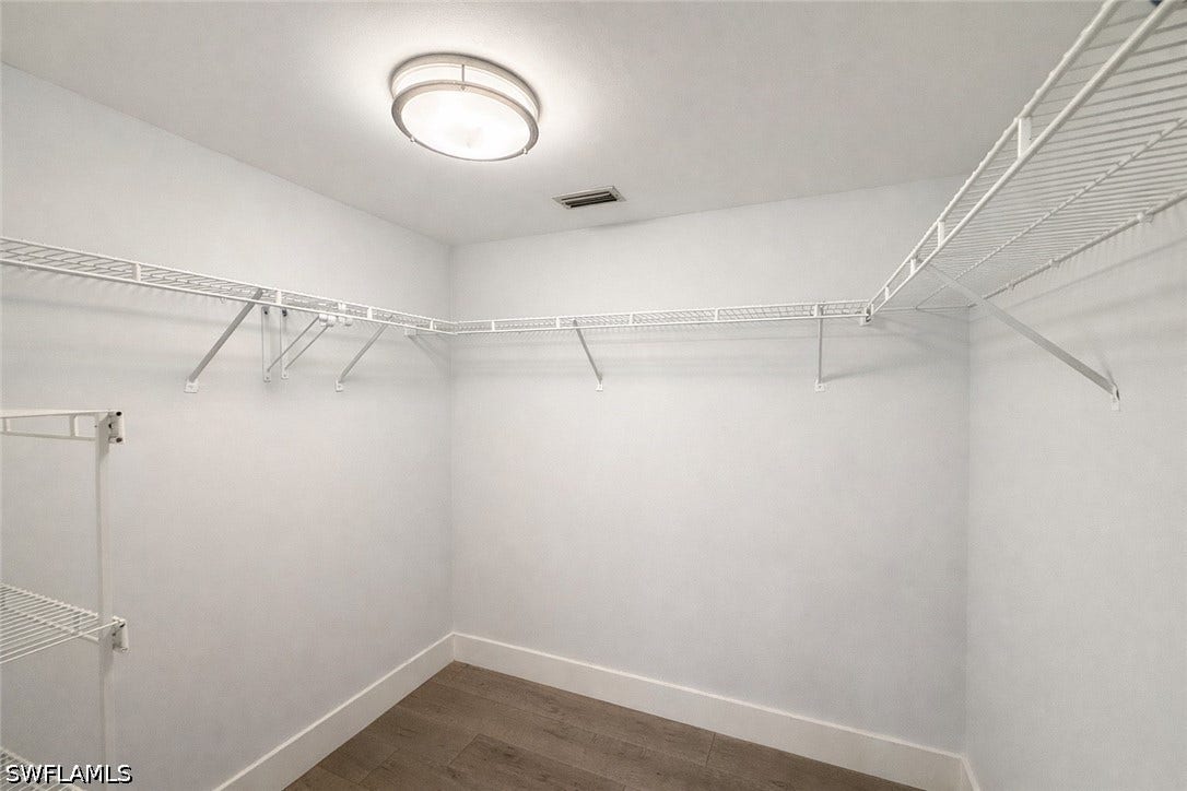 Walk in closet featuring dark wood-type flooring