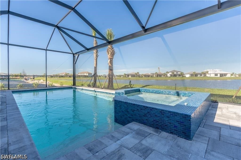 Screened-in outdoor living space featuring a swimming pool, integrated spa with blue mosaic tile, and paver patio