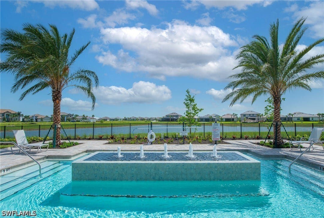 Resort-style aquatic area featuring a swimming pool, integrated fountain, and a paved deck