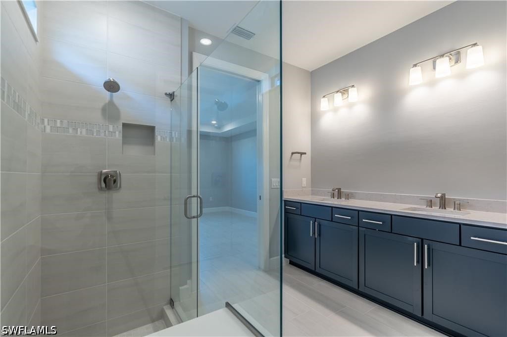 Spacious bathroom with dual vanity, dark cabinetry, and stone countertops