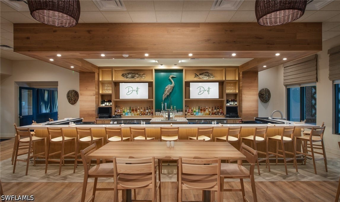 Expansive bar area featuring a wood-finish counter, built-in shelving, wood-finish flooring, and recessed lighting