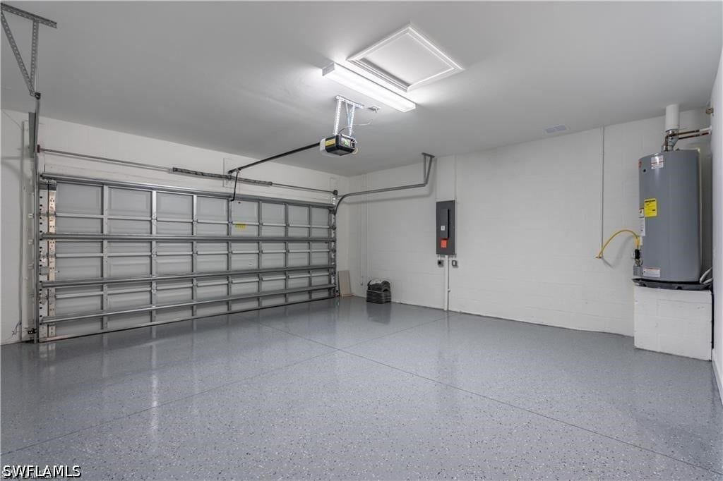 Attached garage featuring a sectional overhead door, automatic opener, epoxy-coated flooring, and a water heater
