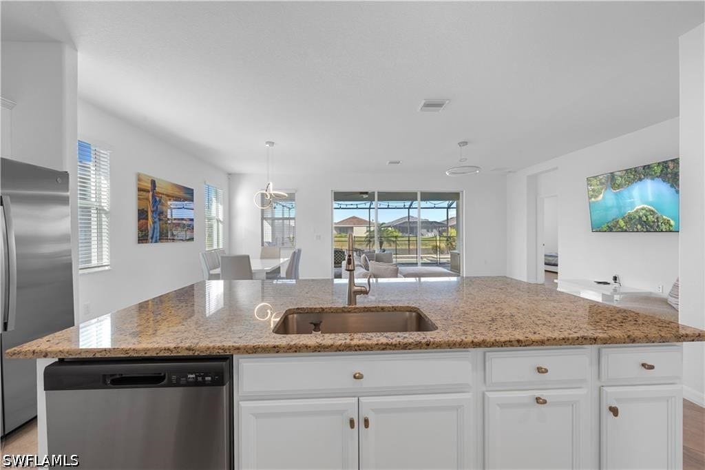 Kitchen island featuring an undermount sink and light-toned stone countertop