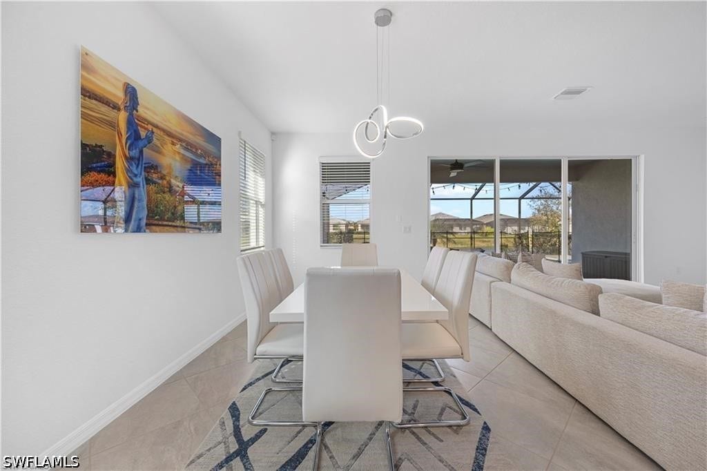 Modern dining space featuring a white rectangular table, upholstered dining chairs with metal frames, and a sculptural pendant light fixture