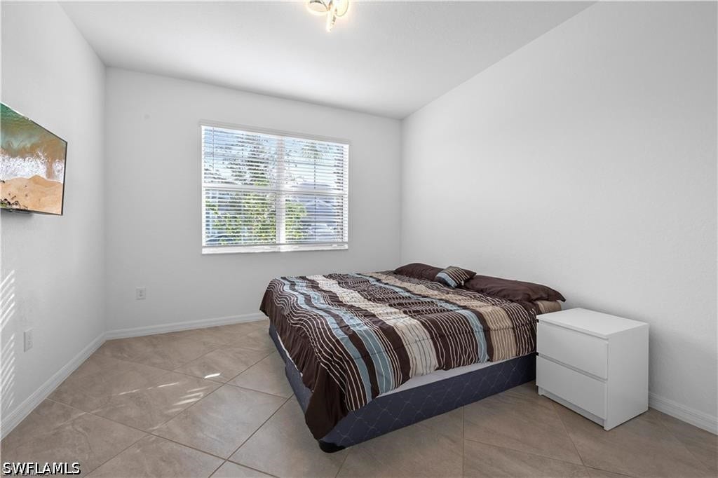 Bedroom featuring tiled flooring, a single window with horizontal blinds, and white walls