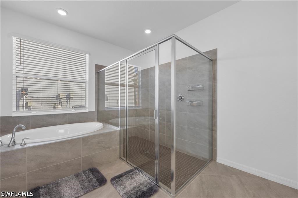 Recessed lighting illuminates a spacious walk-in shower with a glass enclosure and a built-in soaking tub
