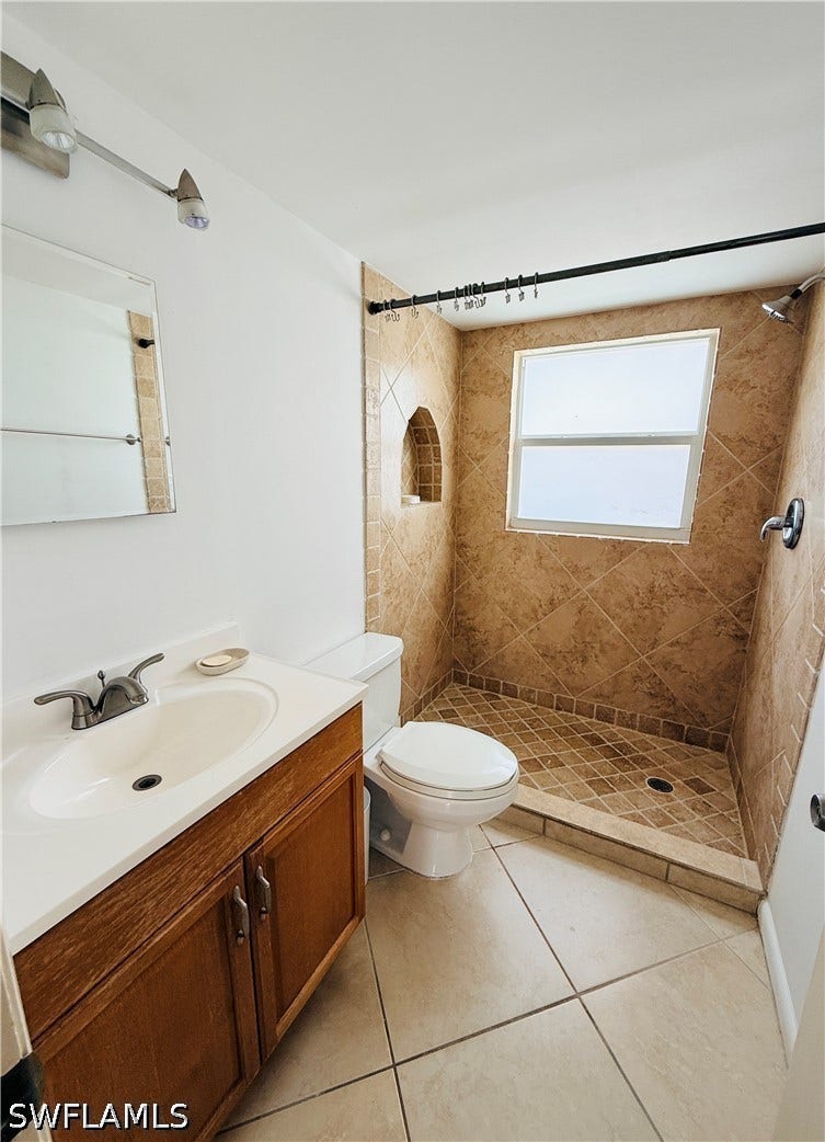 Walk-in shower with tiled walls and floor, featuring an arched recess