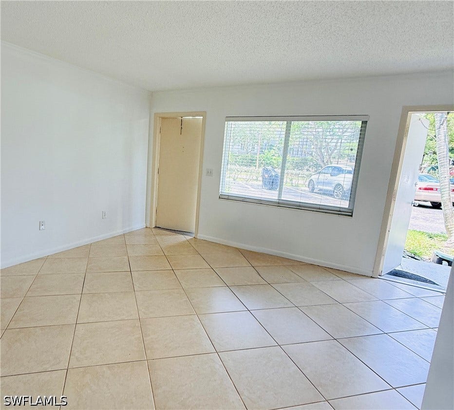 Tile flooring with a neutral finish, white painted walls, and a large window with blinds