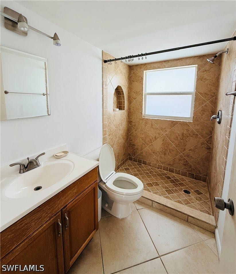 Tiled shower with a window, built-in shower niche, and a vanity with an integrated sink