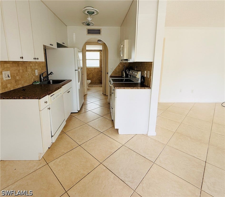 Kitchen featuring white cabinetry, granite-style countertops, mosaic tile backsplash, and tile flooring