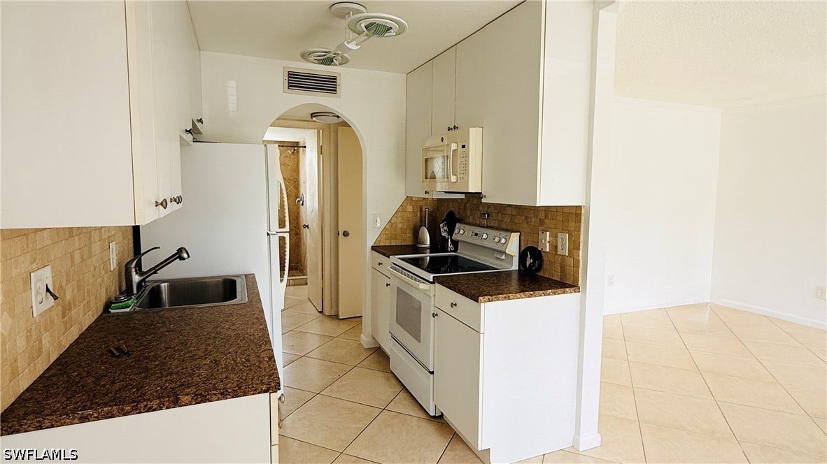 Kitchen featuring white cabinetry, brown speckled countertops, mosaic tile backsplash, and stainless steel sink
