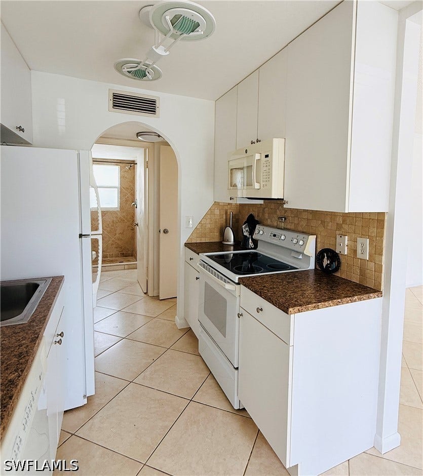Kitchen featuring white cabinetry, brown speckled countertops, and a tiled backsplash