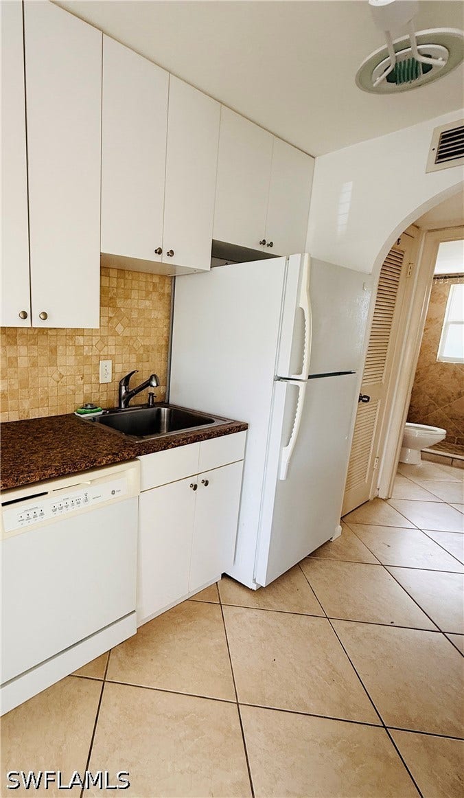 Kitchen featuring white cabinetry, a double basin sink, a built-in dishwasher, and tiled flooring