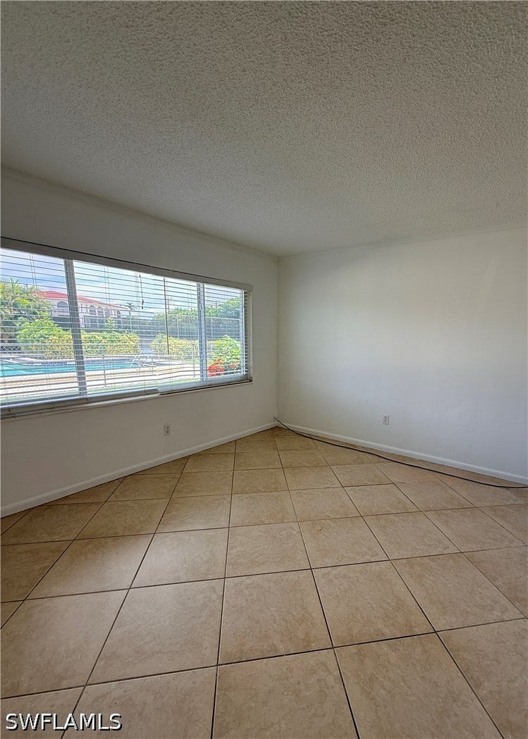 Tiled flooring with large format square tiles, white walls, and horizontal window blinds