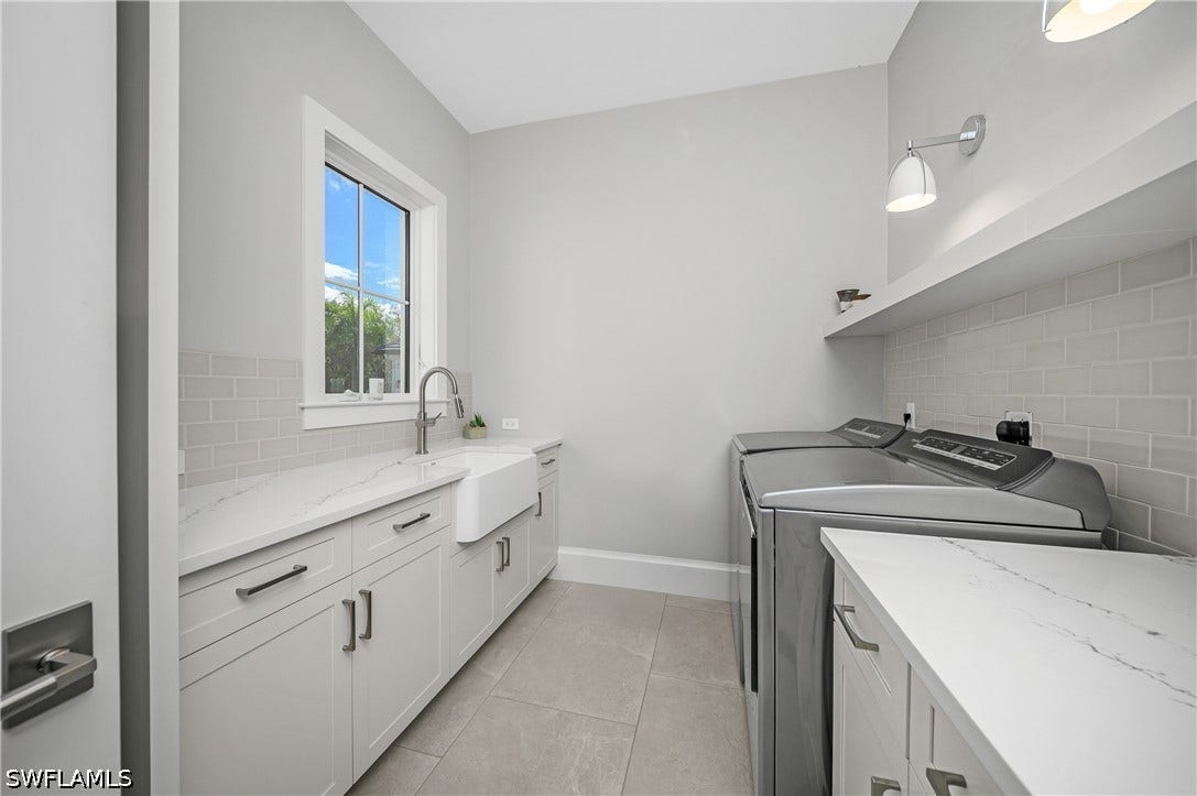 The laundry room has a window providing natural light, utility sink, counter folding space, floor to ceiling pull-out drying racks, sconce lighting, and additional cabinetry.