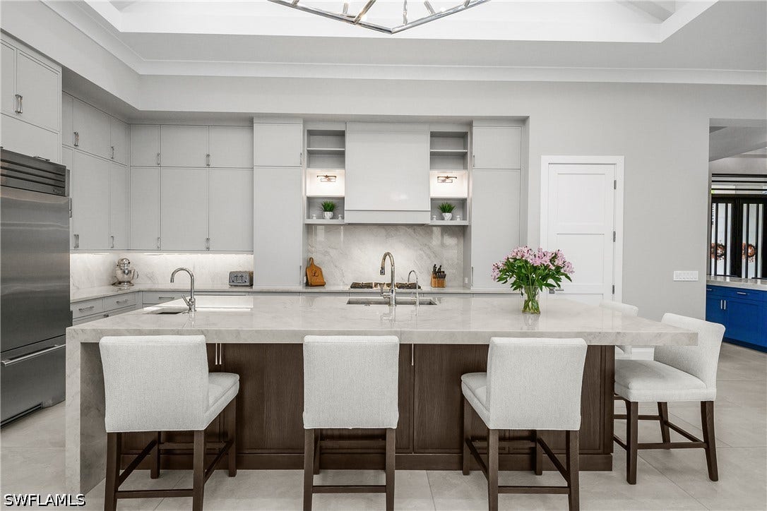 Kitchen includes custom 3" leathered finish quartz waterfall countertop, two Bosch dishwashers, Dual True professional grade refrigerator/freezer, Blue Star professional grade gas range, Stainless steel sink with additional vegetable prep sink.