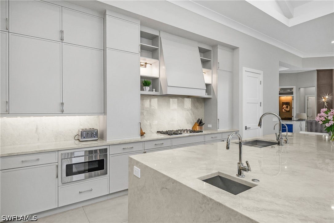 Kitchen features Quartz countertop with matching backsplash, stainless steel sink, added vegetable sink, under counter Sharp microwave drawer, two Bosch dishwashers, Blue Star professional gas range, Dual True professional grade refrigerator/freezer units, and oversized walk-in pantry with custom pull-out shlelving.