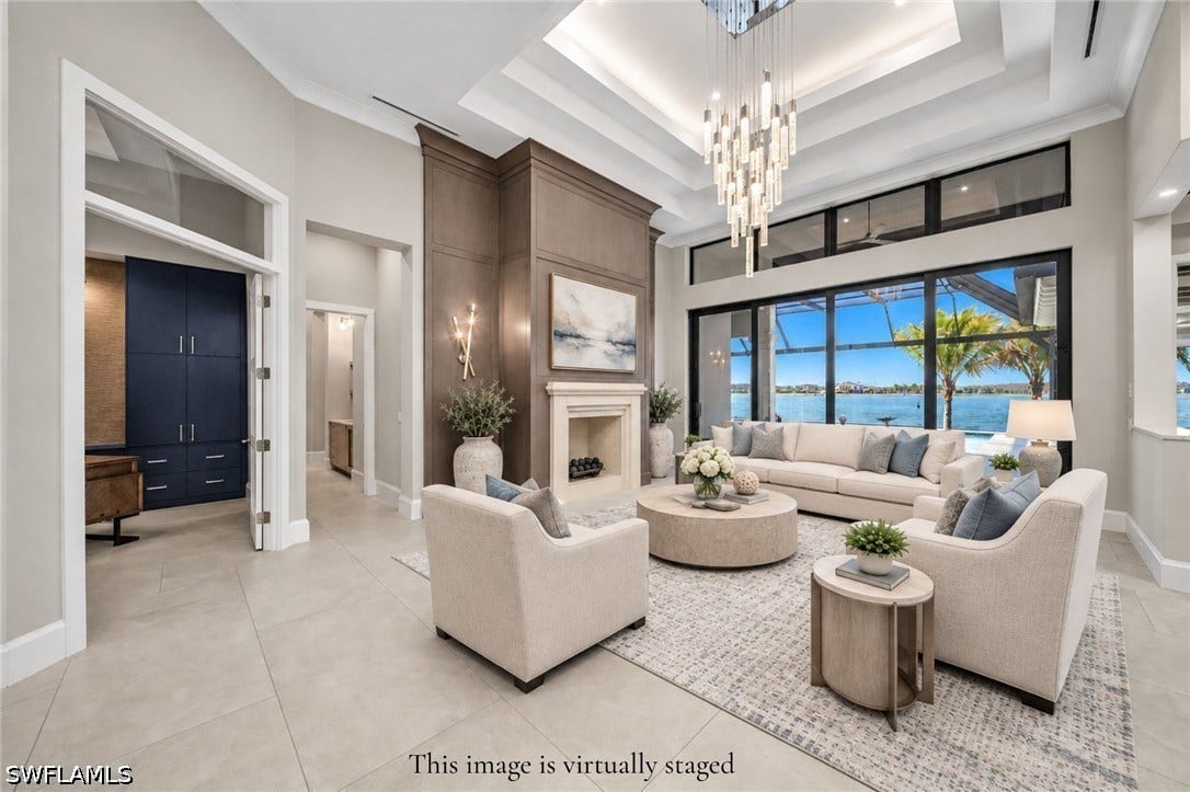 Foyer entrance is stunning with 18' ceilings, precast fireplace with custom white oak walls, impact sliders with transom windows, and a stunning view of Wildblue Lake. *this image is virtually staged