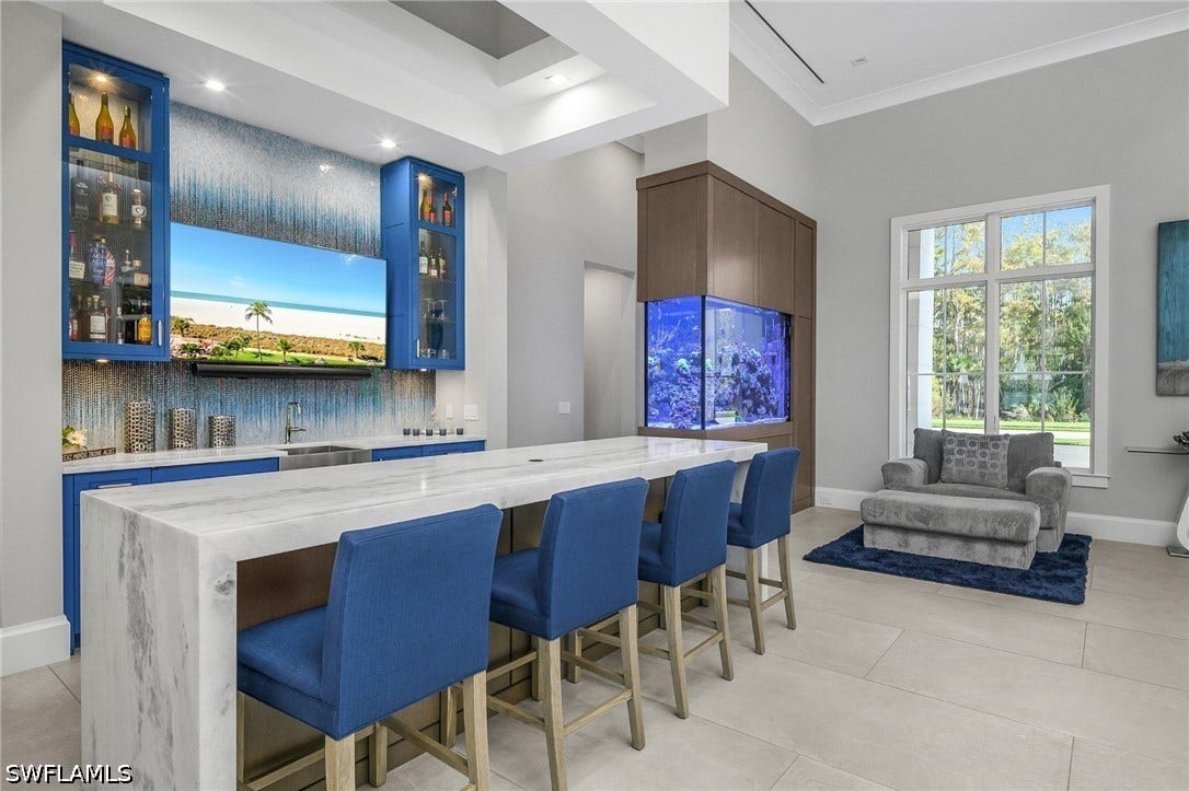 Entry features Custom created dual-sided 400 gallon saltwater aquarium with white oak accent walls.