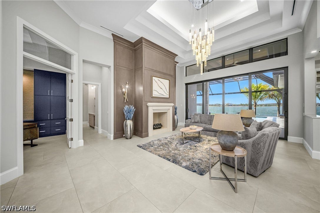 Foyer entrance is stunning with 18' ceilings, precast fireplace with custom white oak walls, impact sliders with transom windows, and a stunning view of Wildblue Lake.
