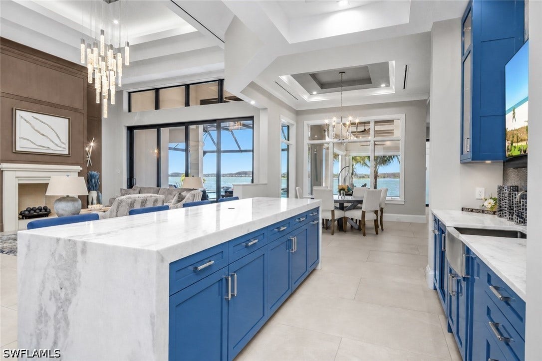 Social bar features modern style cabinetry with glass uppers, leathered waterfall quartz countertops, ombre tile backsplash, Perlick ice maker and beverage cooler.