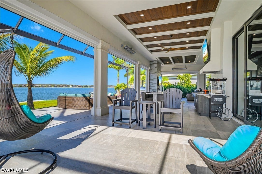Lanai features three panoramic screens for unobstructed lake views, 9 remote storm shades, five overhead outdoor heaters, natural gas fireplace, outdoor kitchen, built-in gas fire pit, tongue and groove ceilings, and travertine pavers.