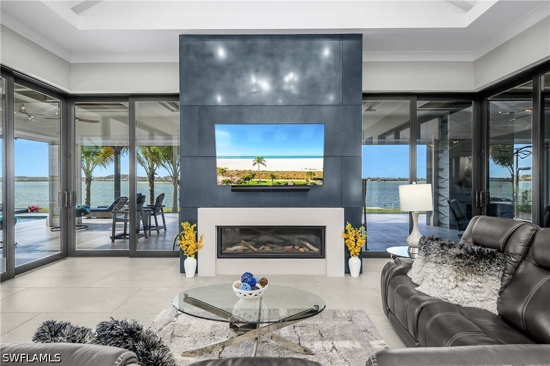 Living room with soaring ceilings: 18' at center, gas fireplace finished with stainless steel metal patina accent.