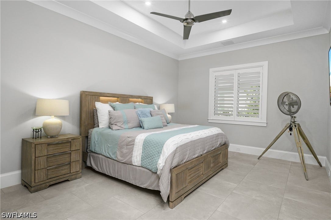 Guest suite #2 with plantation shutters, crown molding, tray ceiling, and ensuite bath.