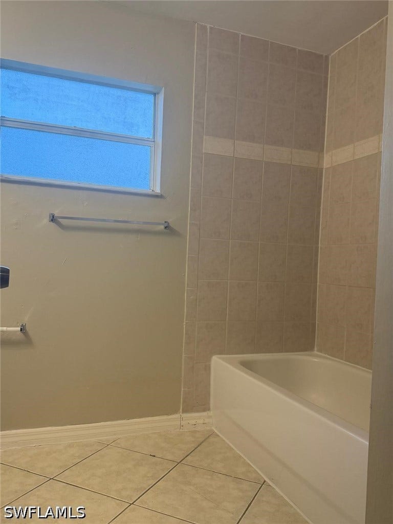 4822/4824 Leonard Boulevard S, Lehigh Acres, FL 33973 Built-in bathtub with tiled surround, light-toned wall paint, and tiled flooring