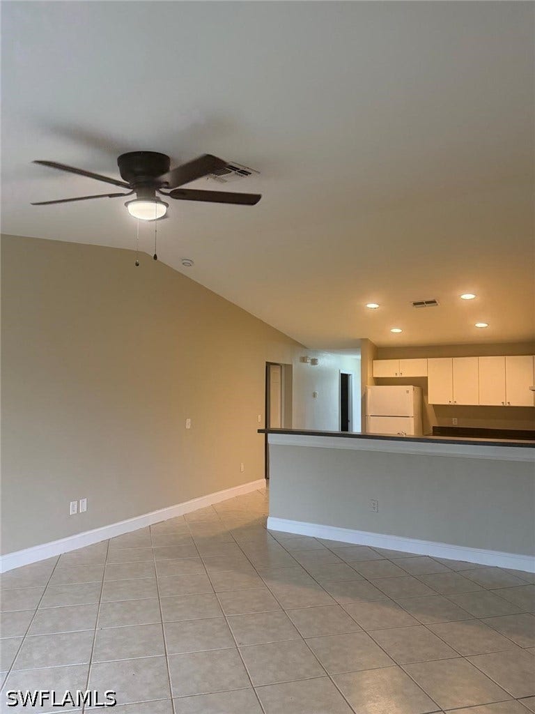 4822/4824 Leonard Boulevard S, Lehigh Acres, FL 33973 Tiled flooring throughout, recessed lighting, ceiling fan with integrated light, and a kitchen featuring a refrigerator and white cabinetry
