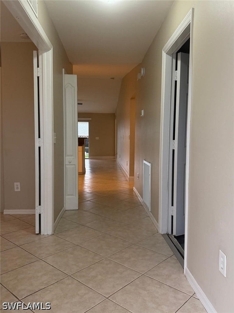 4822/4824 Leonard Boulevard S, Lehigh Acres, FL 33973 Hallway featuring neutral wall paint, white trim, and square tile flooring