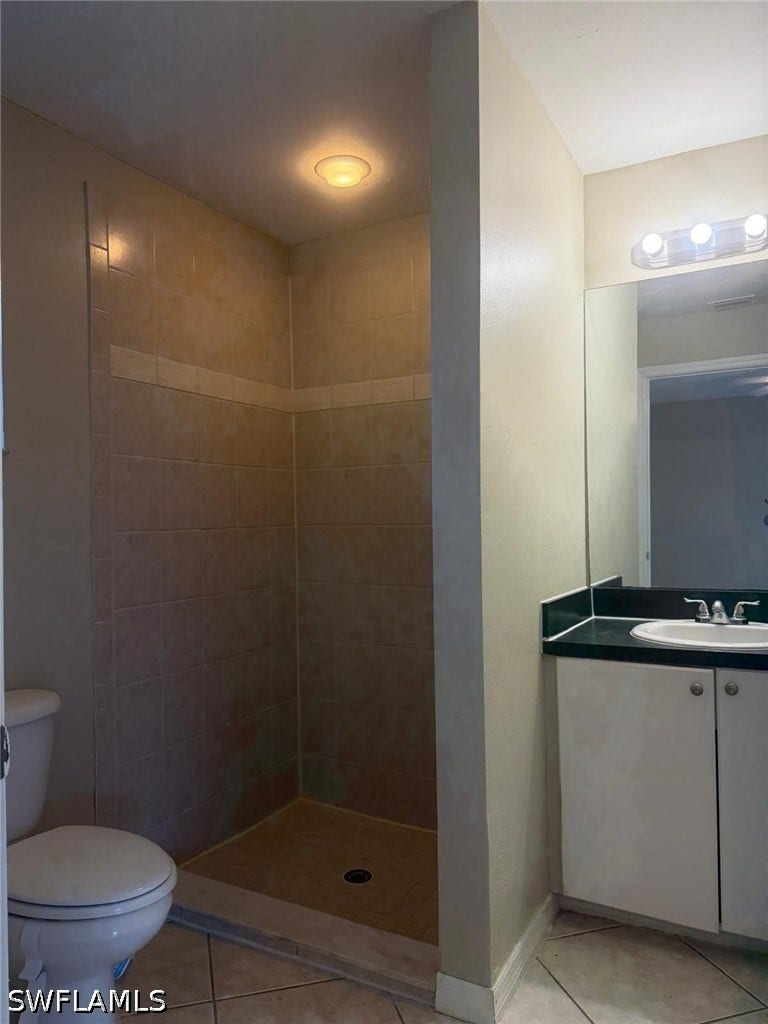 4822/4824 Leonard Boulevard S, Lehigh Acres, FL 33973 Tile flooring, a walk-in shower with tiled walls, a vanity with under-sink storage, and a built-in mirror