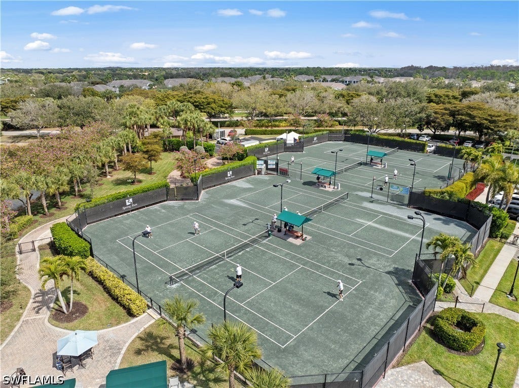 Hard surface tennis courts with perimeter fencing, shaded seating areas, and integrated lighting