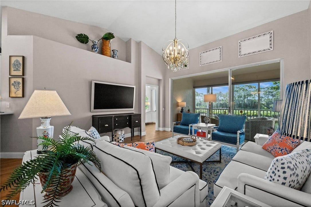 Vaulted ceiling living area with a decorative chandelier, built-in display shelf, and expansive sliding glass doors leading to a screened lanai