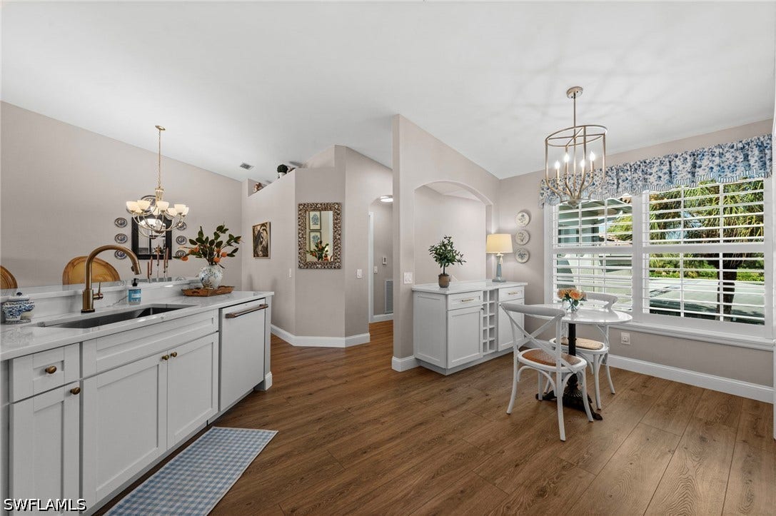 Kitchen featuring white cabinetry, a built-in dishwasher, and a bronze-finish gooseneck faucet