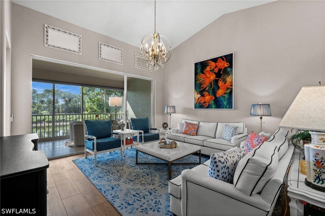 Vaulted ceiling, wood-finish flooring, sliding glass doors, screened lanai, and a decorative chandelier