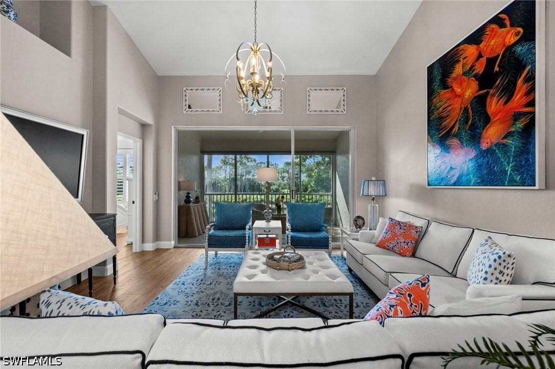 Vaulted ceilings, wood-finish flooring, sliding glass doors, and a decorative chandelier
