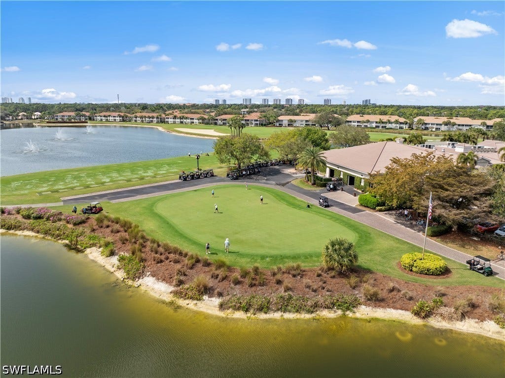 Lush green golf course with adjacent water features, a clubhouse, and mature landscaping