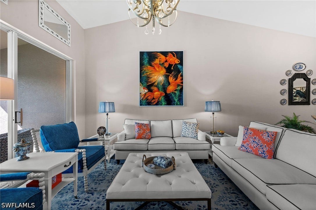 Vaulted ceiling, sliding glass doors, chandelier, and a decorative wall mirror