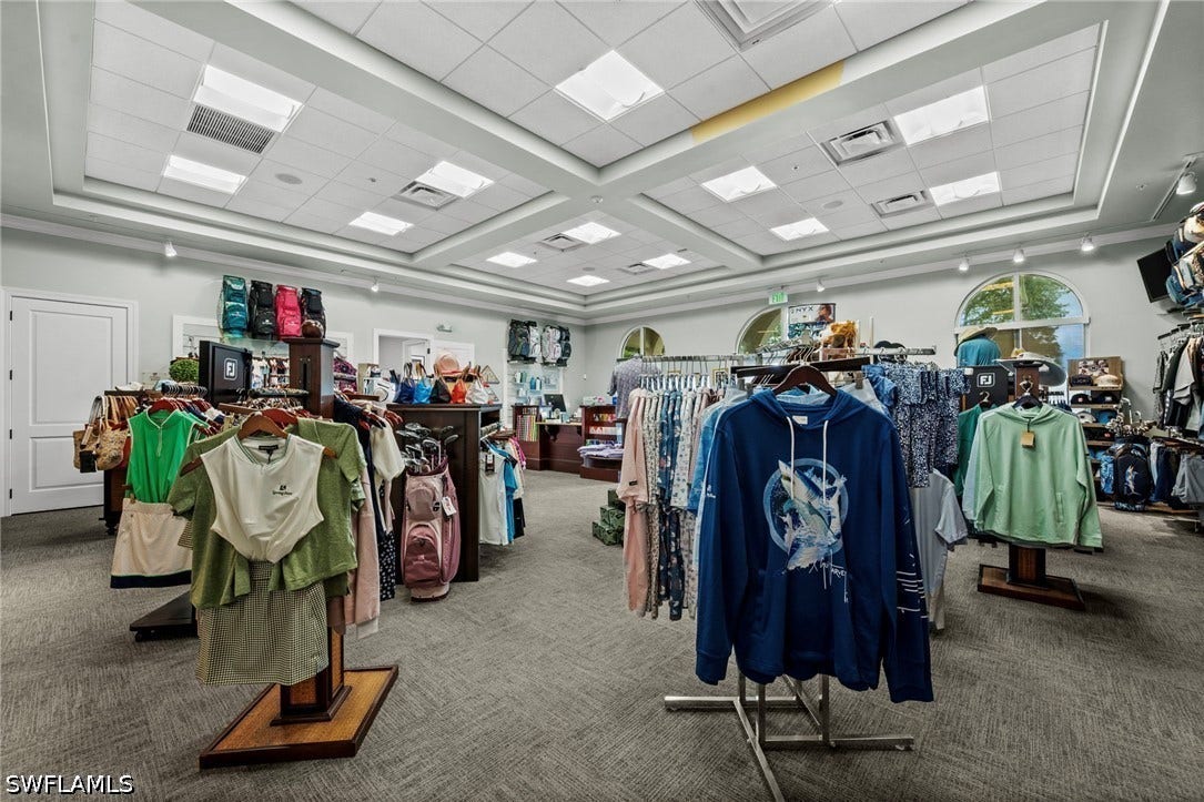 Recessed lighting within a coffered ceiling, neutral-toned carpeting, and arched windows