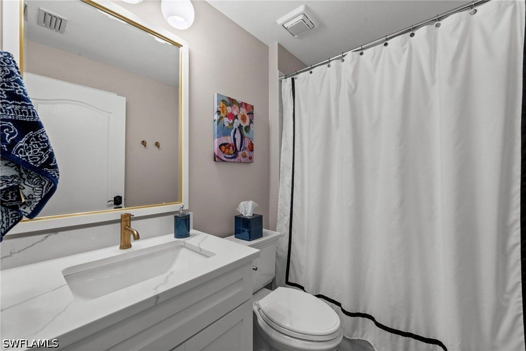 White vanity with integrated sink, gold-finish faucet, and coordinating framed mirror