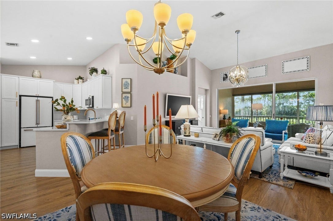 Vaulted ceilings, wood-finish flooring, white kitchen cabinetry, and large sliding glass doors