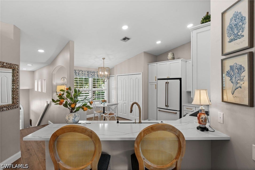 White shaker cabinetry, recessed lighting, and wood-finish flooring