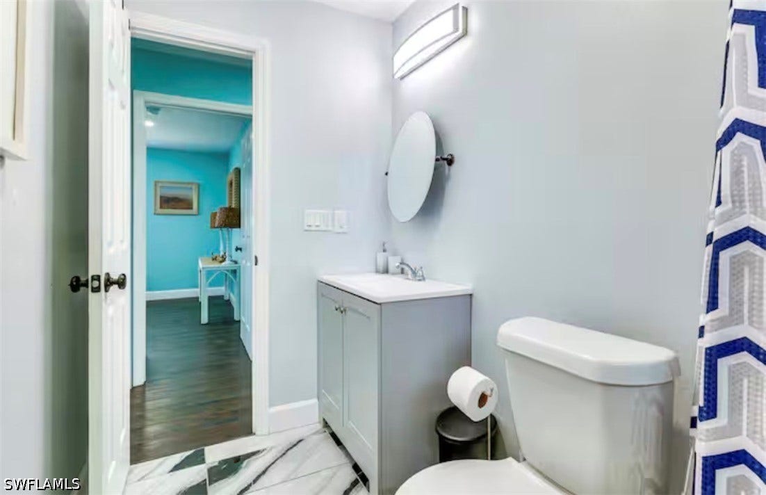 4630 New Haven Drive, Fort Myers, FL 33908 Vanity with integrated sink, sleek wall-mounted light fixture, and round vanity mirror