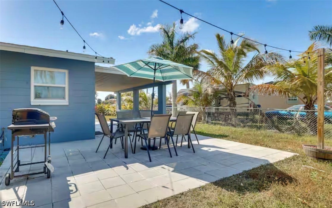 4630 New Haven Drive, Fort Myers, FL 33908 Paved patio area featuring an awning, string lighting, and mature palm trees